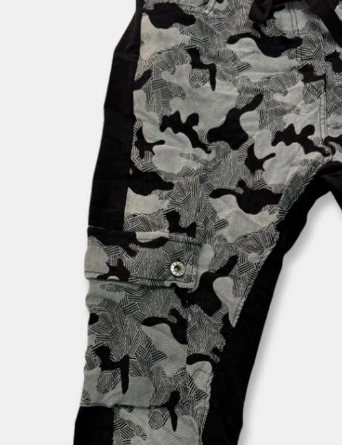Detalle pantalones baggy en colores negro y gris con estampado de camuflaje. Cierre con cordón ajustable y cintura elástica. Bolsillos.