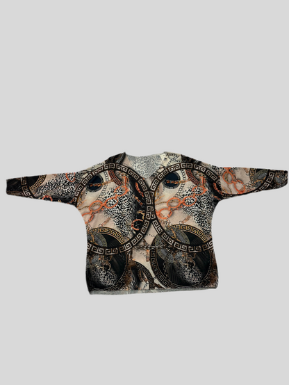 Jersey de punto fino, con cuello redondo y dibujos cenefas griegas en tonos negros, beige y naranja. Corte oversize.