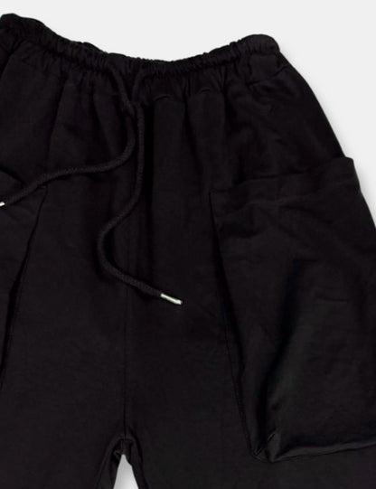 Detalle pantalones baggy negros con bolsillos, cintura elástica y cordón de ajuste para mujer de talla curvy.