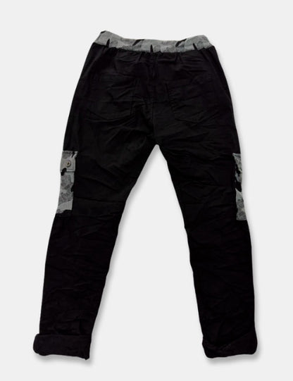 Pantalones baggy en colores negro y gris con estampado de camuflaje. Cierre con cordón ajustable y cintura elástica. Bolsillos.