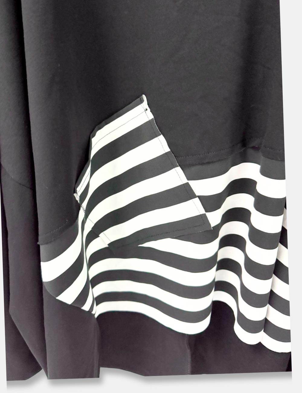 Detalle sudadera color negro, con detalle de faldón y parche en rayas blancas y negra. Abertura lateral. Talla curvy.